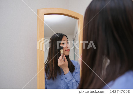 晨間日常:一位女士一邊化妝一邊照鏡子。 晨間日常:一位女士一邊化妝一邊照鏡子。 142747008