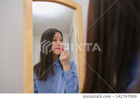 晨間日常：一位女士一邊化妝一邊照鏡子。 142747009