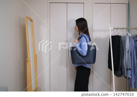 一位女士照鏡子,準備去上班。 一位女士照鏡子,準備去上班。 142747010