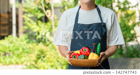 一名男子手持新鮮採摘的夏季蔬菜。這幅畫面讓人聯想到農民、生產者、產地直送以及故鄉稅捐贈制度。 一名男子手持新鮮採摘的夏季蔬菜。這幅畫面讓人聯想到農民、生產者、產地直送以及故鄉稅捐贈制度。 142747743