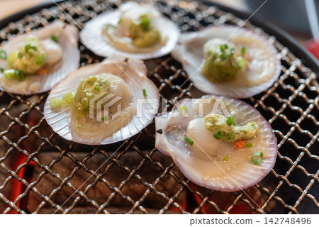 Fresh scallops grilled shells garlic herb butter chopped green onion over hot charcoal representing delicious seafood barbecue restaurant cuisine Fresh scallops grilled shells garlic herb butter chopped green onion over hot charcoal representing delicious seafood barbecue restaurant cuisine 142748496