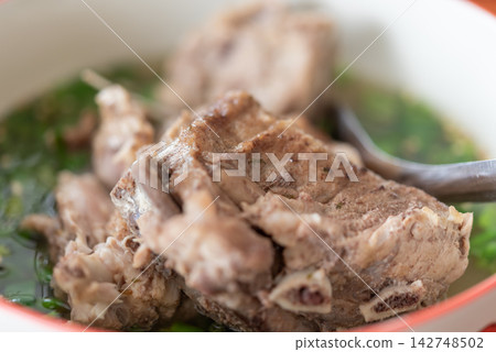 Thai pork bone soup tender meat fresh green herbs clear savory broth served hot as traditional homemade Asian comfort food Thai pork bone soup tender meat fresh green herbs clear savory broth served hot as traditional homemade Asian comfort food 142748502