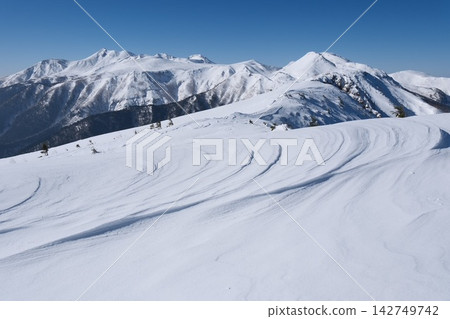 美麗的雪景在晴朗的藍天下,被風吹拂成各種形狀,白雪皚皚的山脈巍峨聳立。 美麗的雪景在晴朗的藍天下,被風吹拂成各種形狀,白雪皚皚的山脈巍峨聳立。 142749742