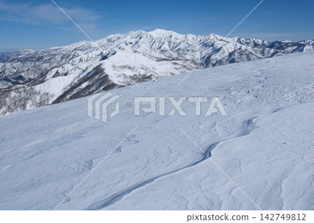 風吹起的積雪覆蓋了廣闊的山坡,遠處還有閃閃發光的雪山。 風吹起的積雪覆蓋了廣闊的山坡,遠處還有閃閃發光的雪山。 142749812