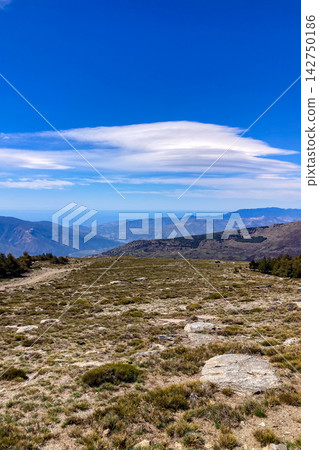 A hiking trail leads toward snow capped peaks revealing dramatic alpine terrain expansive vistas and crisp winter light in the Sierra Nevada Mountains in Spain A hiking trail leads toward snow capped peaks revealing dramatic alpine terrain expansive vistas and crisp winter light in the Sierra Nevada Mountains in Spain 142750186