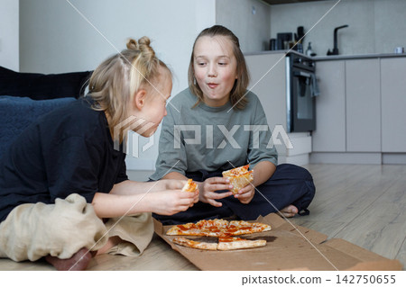 Happy children eating pizza and having fun wile sitting on floor 142750655