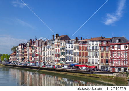 Historical houses line the scenic Nive river embankment in Bayonne, France. Bright daylight showcases traditional style, no people Historical houses line the scenic Nive river embankment in Bayonne, France. Bright daylight showcases traditional style, no people 142750729