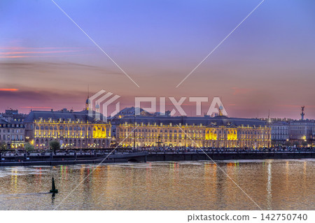 Illuminated Place de la Bourse facade viewed from across Garonne river at sunset in Bordeaux, France. Grand night illumination Illuminated Place de la Bourse facade viewed from across Garonne river at sunset in Bordeaux, France. Grand night illumination 142750740