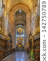Interior view of Basilica of Saint-Sernin in Toulouse, France. Historic wooden church pews near altar under soft light 142750789