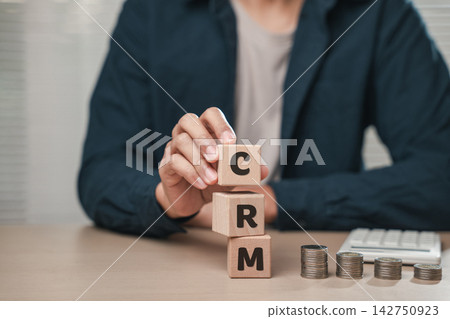 Close up businessman hand holding wooden cube blocks spelling CSR near coins and a calculator. Represents Corporate Social Responsibility, planning, employee performance tracking Close up businessman hand holding wooden cube blocks spelling CSR near coins and a calculator. Represents Corporate Social Responsibility, planning, employee performance tracking 142750923