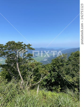 鬱鬱蔥蔥的山頂景色，俯瞰藍天和山脈。 142751123