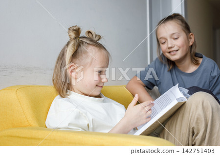 Happy children reading a book at home. Blonde sibling 11 and 7 years old Happy children reading a book at home. Blonde sibling 11 and 7 years old 142751403