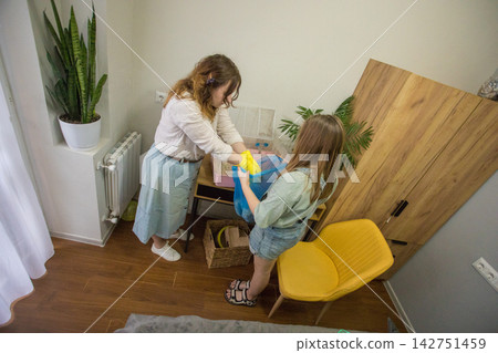 Two individuals work together in a room to clean a pet hamster cage. 142751459