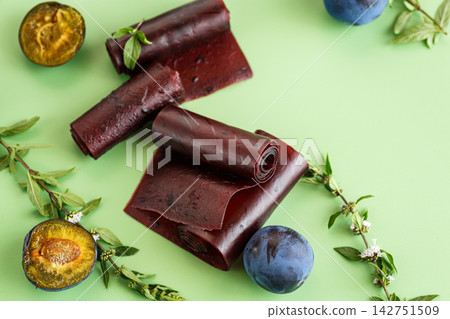 Healthy plum fruit leather with fresh fruit on light green background Healthy plum fruit leather with fresh fruit on light green background 142751509