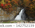 A rainbow falls into the waterfall basin amidst autumn leaves. 142752139