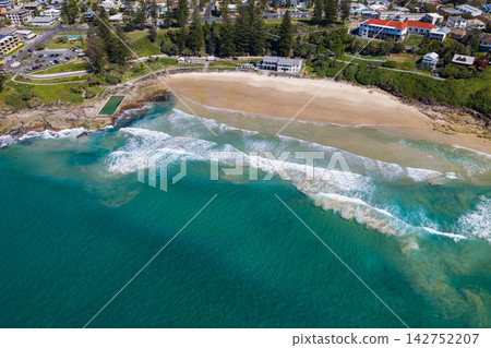 Aerial view of Yamba Ocean Pool beside Main Beach, showing the sandy shoreline, coastal headland and blue waters of the Pacific Ocean in New South Wales, Australia. Aerial view of Yamba Ocean Pool beside Main Beach, showing the sandy shoreline, coastal headland and blue waters of the Pacific Ocean in New South Wales, Australia. 142752207
