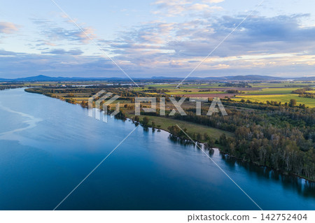 Aerial view over the expansive Clarence River and surrounding farmland near Yamba, showing the broad waterway winding through the rural landscape beneath a softly clouded sky Aerial view over the expansive Clarence River and surrounding farmland near Yamba, showing the broad waterway winding through the rural landscape beneath a softly clouded sky 142752404