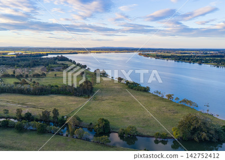 Aerial view of Romiaka Channel and the Clarence River winding through farmland on Palmers Island near Yamba, with cultivated fields, rural vegetation and waterways extending across the landscape Aerial view of Romiaka Channel and the Clarence River winding through farmland on Palmers Island near Yamba, with cultivated fields, rural vegetation and waterways extending across the landscape 142752412