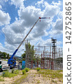 A rough terrain crane working under a blue sky at a construction site. 142752865