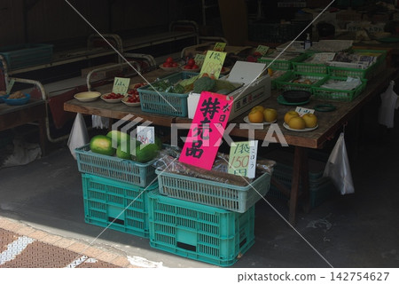 An outdoor market stall displaying fruits and vegetables 142754627