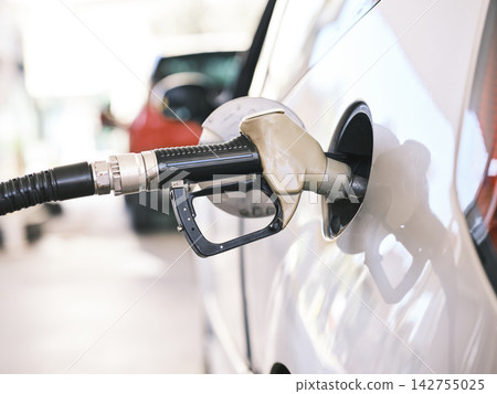 Gas pump nozzle in the fuel tank of a gray car, refuel Gas pump nozzle in the fuel tank of a gray car, refuel 142755025