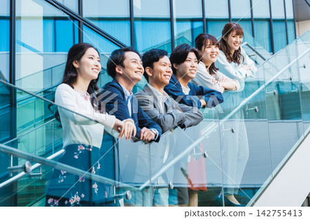A young business team smiles in front of the building. A young business team smiles in front of the building. 142755413