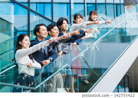 一群年輕的商務人士在辦公大樓前微笑合照。 一群年輕的商務人士在辦公大樓前微笑合照。 142755422