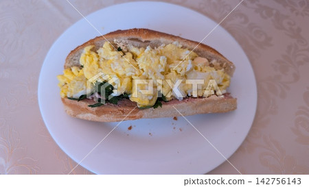 Homemade egg sandwich with scrambled eggs and herbs on a white plate Homemade egg sandwich with scrambled eggs and herbs on a white plate 142756143