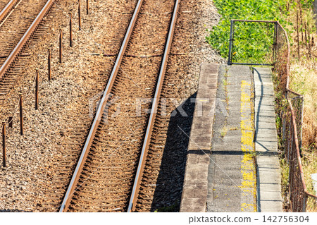High-angle shot of the ballast track and the side of the tracks in a double-track section with a wire mesh fence. High-angle shot of the ballast track and the side of the tracks in a double-track section with a wire mesh fence. 142756304