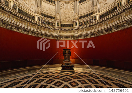 Elliptical domed chapter house of Seville Cathedral with red damask walls and archbishop's throne 142756491