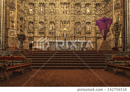 Golden Gothic altarpiece of Seville Cathedral seen from the nave with pews and steps 142756516