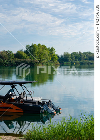 Vertical view of a modern tourist boat docked on a calm river lake surface 142756839