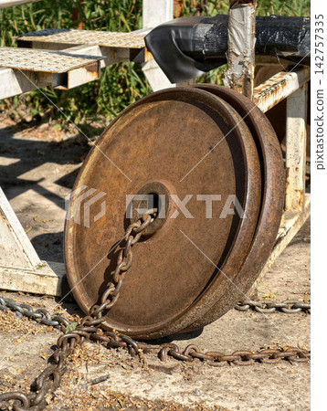 Old chained iron weight plates on an outdoor sports ground with weathered homemade exercise equipment for resistance training and fitness workouts Old chained iron weight plates on an outdoor sports ground with weathered homemade exercise equipment for resistance training and fitness workouts 142757335