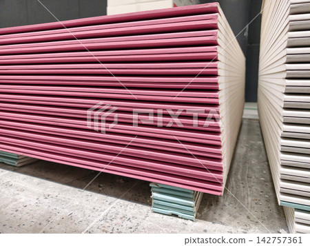 Red drywall panels stacked on pallets in a large construction warehouse Red drywall panels stacked on pallets in a large construction warehouse 142757361
