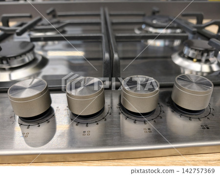 Detailed view of knobs on built in gas stove, metal surface with burners and oven, ergonomic design for home kitchen cooking Detailed view of knobs on built in gas stove, metal surface with burners and oven, ergonomic design for home kitchen cooking 142757369