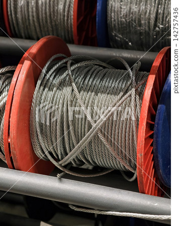 Metal wire rope tightly wound on a spool showcasing durable construction materials designed for industrial, commercial, and maintenance applications 142757436