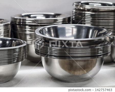 Stacked metal bowls with polished stainless finish displayed on supermarket shelves, highlighting kitchenware designed for durability and efficient everyday cooking use Stacked metal bowls with polished stainless finish displayed on supermarket shelves, highlighting kitchenware designed for durability and efficient everyday cooking use 142757463