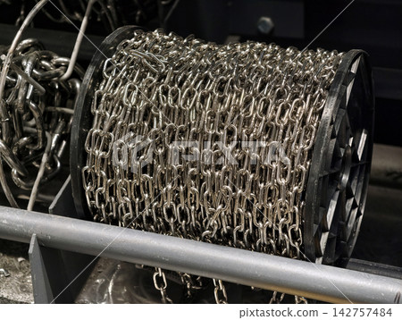 Metal chains arranged on stacked spool reels in a hardware store showcasing systematic storage of strong and versatile metal components Metal chains arranged on stacked spool reels in a hardware store showcasing systematic storage of strong and versatile metal components 142757484