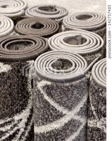 Rolled rugs featuring elegant patterns and carefully crafted woven surfaces 142757485