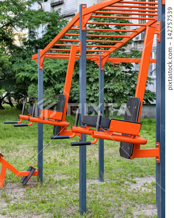 Public outdoor fitness area with permanent exercise equipment in a residential neighborhood for workout sessions and physical culture Public outdoor fitness area with permanent exercise equipment in a residential neighborhood for workout sessions and physical culture 142757539