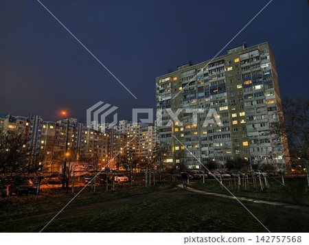 Night view of urban apartments glowing with light, streets below quiet but alive Night view of urban apartments glowing with light, streets below quiet but alive 142757568