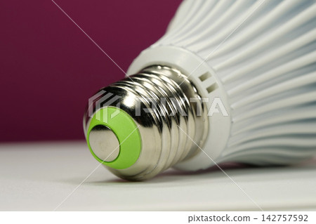 White energy saving LED lamp with E27 screw cap on pink background, close-up White energy saving LED lamp with E27 screw cap on pink background, close-up 142757592