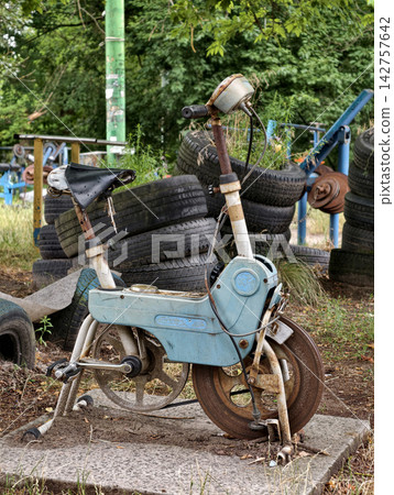 Old rusty Soviet exercise bicycle standing outdoors on a sports area for cardio workouts, physical training and outdoor fitness activities Old rusty Soviet exercise bicycle standing outdoors on a sports area for cardio workouts, physical training and outdoor fitness activities 142757642