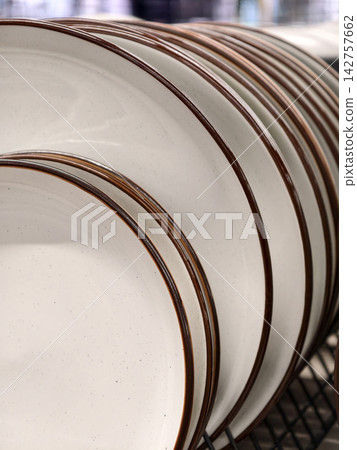 Light ceramic plates with brown rim on shelves, close up of beautiful dishes in various sizes Light ceramic plates with brown rim on shelves, close up of beautiful dishes in various sizes 142757662