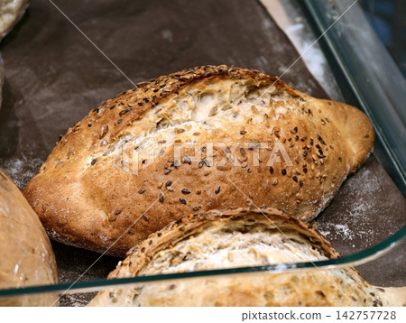 White bread topped with seeds displayed in the bread section of a supermarket, showing fresh bakery products offered to grocery store customers White bread topped with seeds displayed in the bread section of a supermarket, showing fresh bakery products offered to grocery store customers 142757728