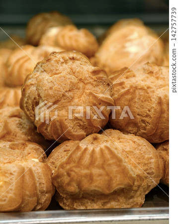 Profiteroles are displayed in a confectionery shop, presenting an appealing selection of delicate pastries filled with sweet cream and arranged for customers Profiteroles are displayed in a confectionery shop, presenting an appealing selection of delicate pastries filled with sweet cream and arranged for customers 142757739
