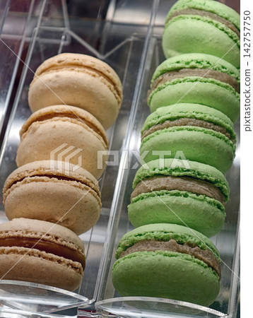 Green and light brown macaron pastries arranged in a pastry shop showcase, presenting an attractive selection of delicate sweet treats with colorful shells and elegant appearance Green and light brown macaron pastries arranged in a pastry shop showcase, presenting an attractive selection of delicate sweet treats with colorful shells and elegant appearance 142757750
