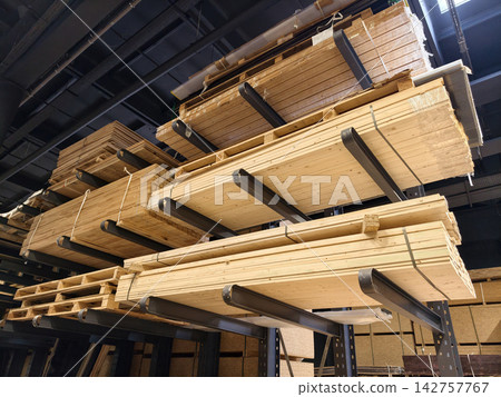 OSB panels, MDF boards, particle boards and wooden planks are stored in organized stacks on multi level industrial racks within a timber warehouse facility OSB panels, MDF boards, particle boards and wooden planks are stored in organized stacks on multi level industrial racks within a timber warehouse facility 142757767