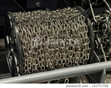 Steel chains wound tightly on commercial spools displayed in a retail environment emphasizing organized inventory of essential construction hardware 142757768