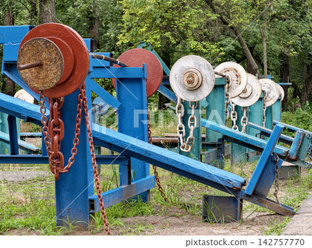 Iron barbells and angled exercise benches arranged on an open air sports ground for incline bench press, bodybuilding and upper body workouts Iron barbells and angled exercise benches arranged on an open air sports ground for incline bench press, bodybuilding and upper body workouts 142757770